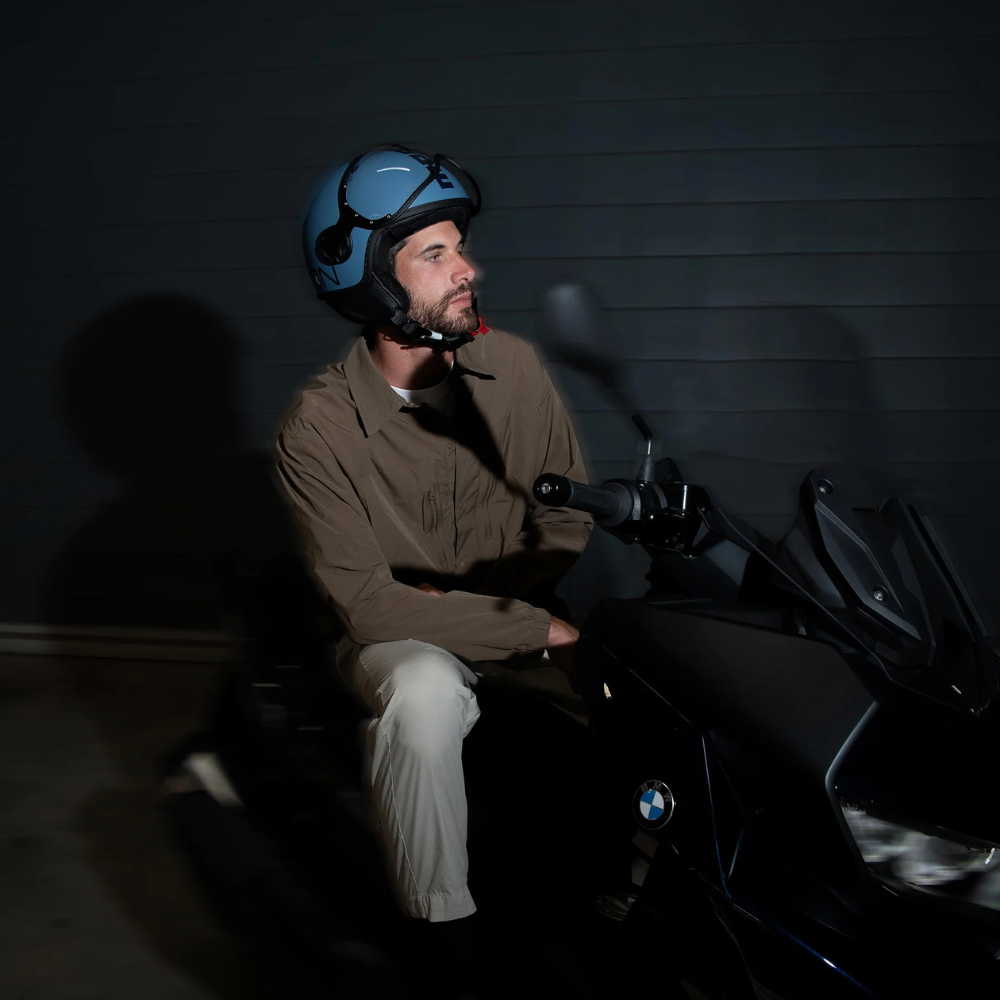 Uomo in sella a uno scooter indossa il casco jet Momo Design FGTR Classic blu polvere opaco