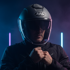 Casco Airoh H.20 grigio scuro indossato di fronte, con neon viola e azzurri sul fondo