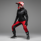 Pilota in piedi con giacca nera e pantaloni rossi e casco Airoh Twist 2.0 Frame rosso opaco, in studio