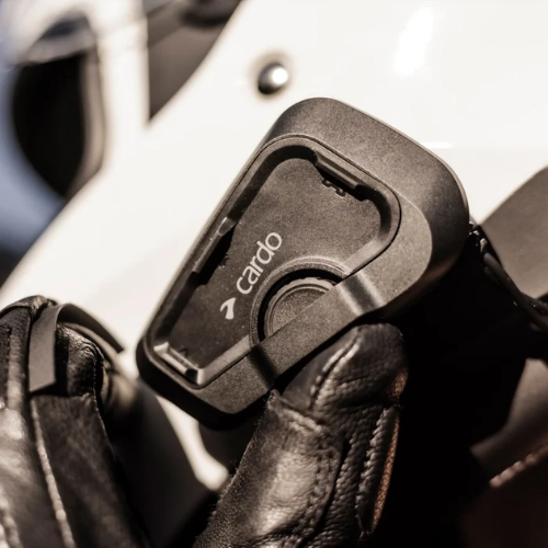Mano con guanto da moto che usa la ruota dei controlli del Cardo Freecom 2X sul casco