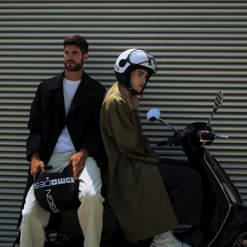 Casco jet Momo Design FGTR Classic Mono nero opaco con scritte bianche tenuto in mano, ambientazione di citta