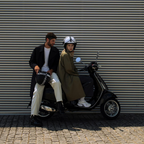 Casco jet Momo Design FGTR Classic Mono nero opaco tenuto in mano accanto a uno scooter, ambientazione urbana