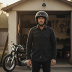 Uomo col casco jet Vespa Colors nero opaco davanti a un garage con una moto classica
