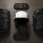 Casco jet Vespa Nazioni 2.0 Inghilterra appoggiato a terra fra una giacca in pelle e guanti da moto