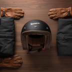 Casco jet Vespa P-Xential nero opaco su tavolo di legno accanto a guanti e giacca
