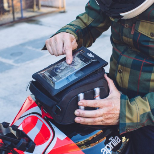 Motociclista che usa il telefono nel porta telefono Kappa AVSH sulla borsa serbatoio, immagine illustrativa