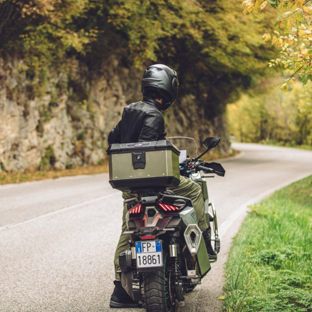 Bauletto Kappa in alluminio verniciato verde montato dietro il pilota di una moto su strada di montagna