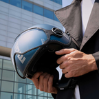 Dettaglio del casco jet Momo Design FGTR EVO blu avio opaco/silver tenuto in mano davanti a un edificio in vetro
