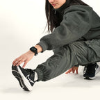 Ragazza in tuta verde durante lo stretching con l'orologio intelligente Momo Design Stealth al polso