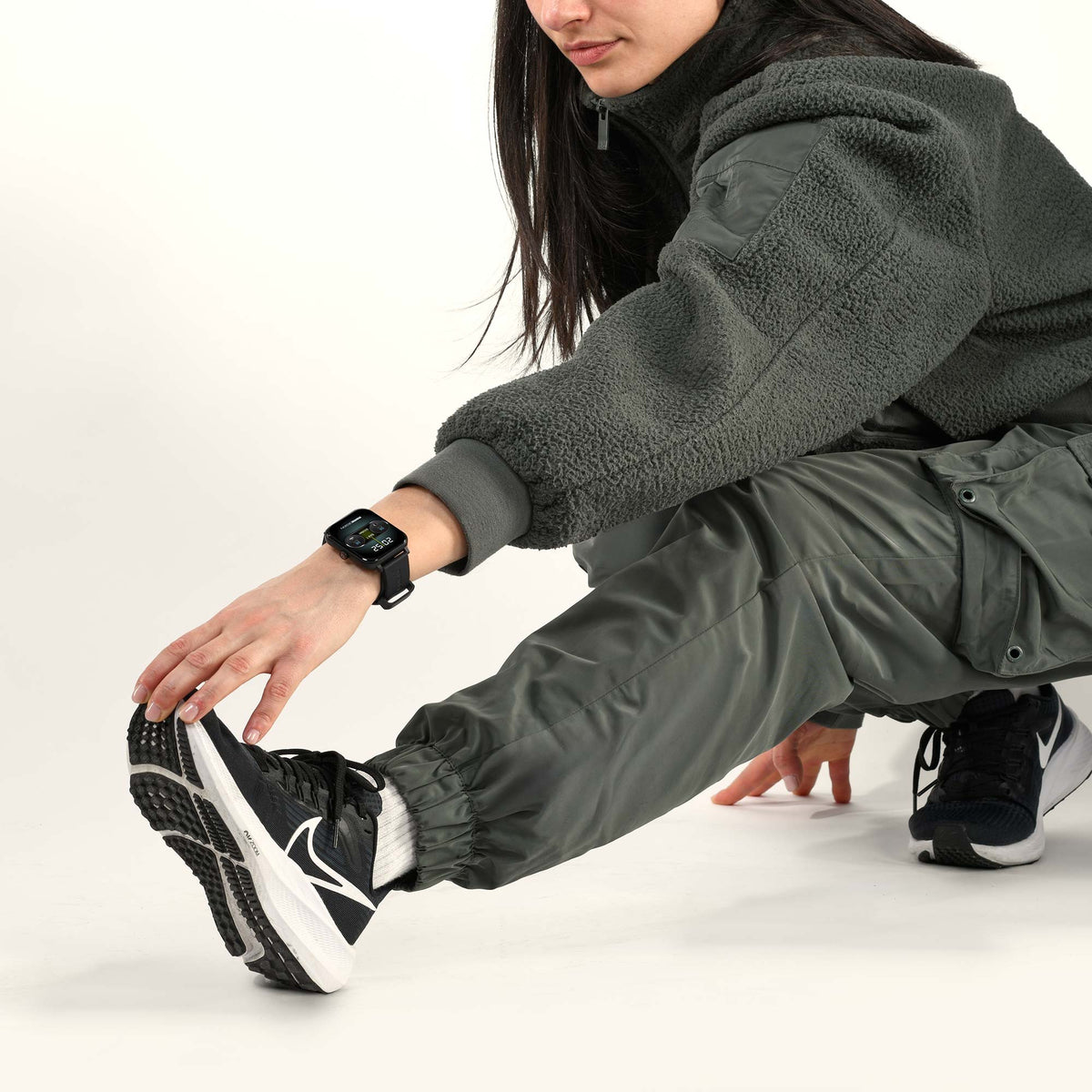 Ragazza in tuta verde durante lo stretching con l'orologio intelligente Momo Design Stealth al polso